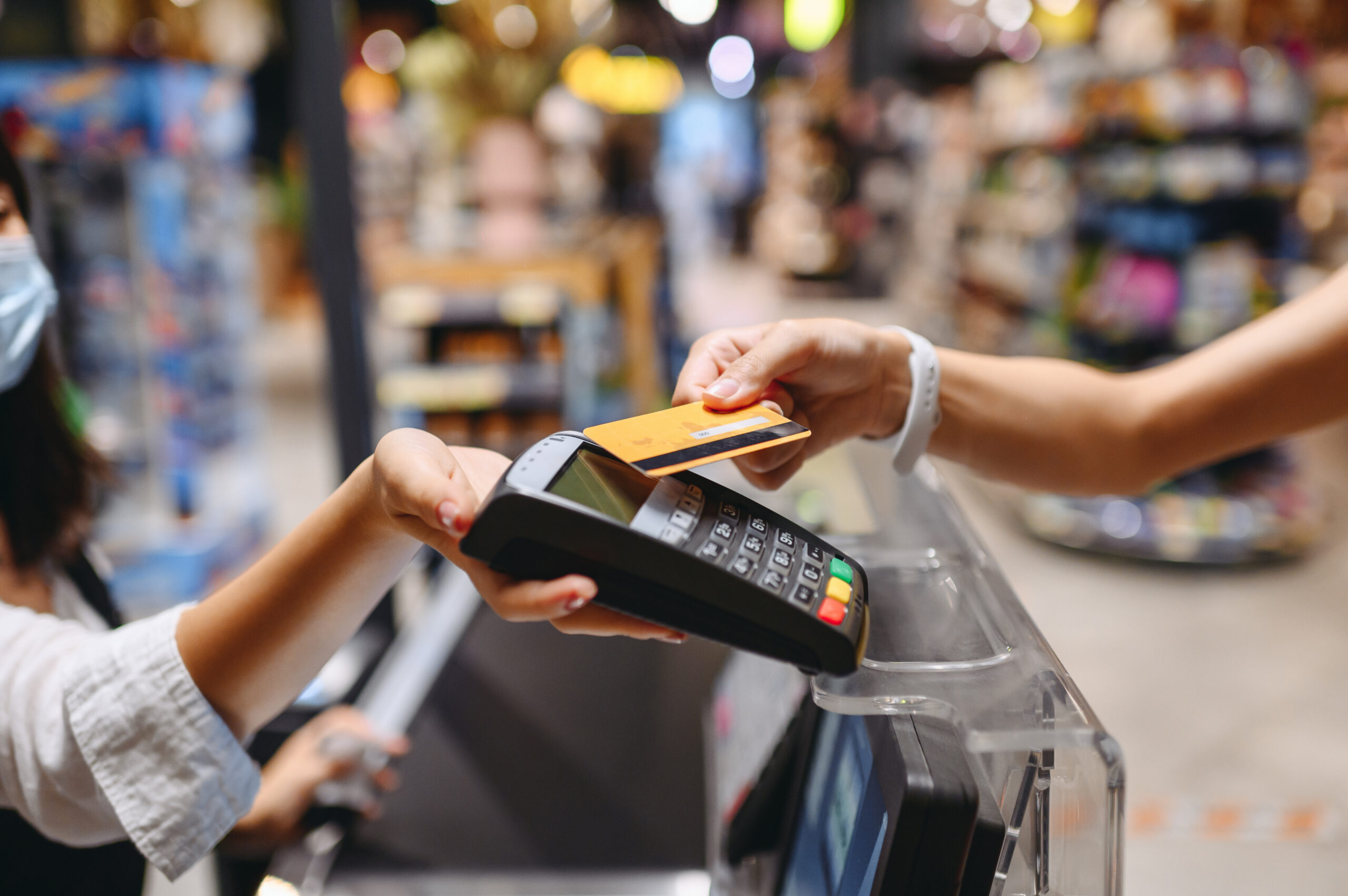 Cropped close up woman hand arm shopping at supermaket put credit card to wireless modern bank payment terminal process acquire payments near cashier checkout inside store. People purchasing concept. customer payment processing