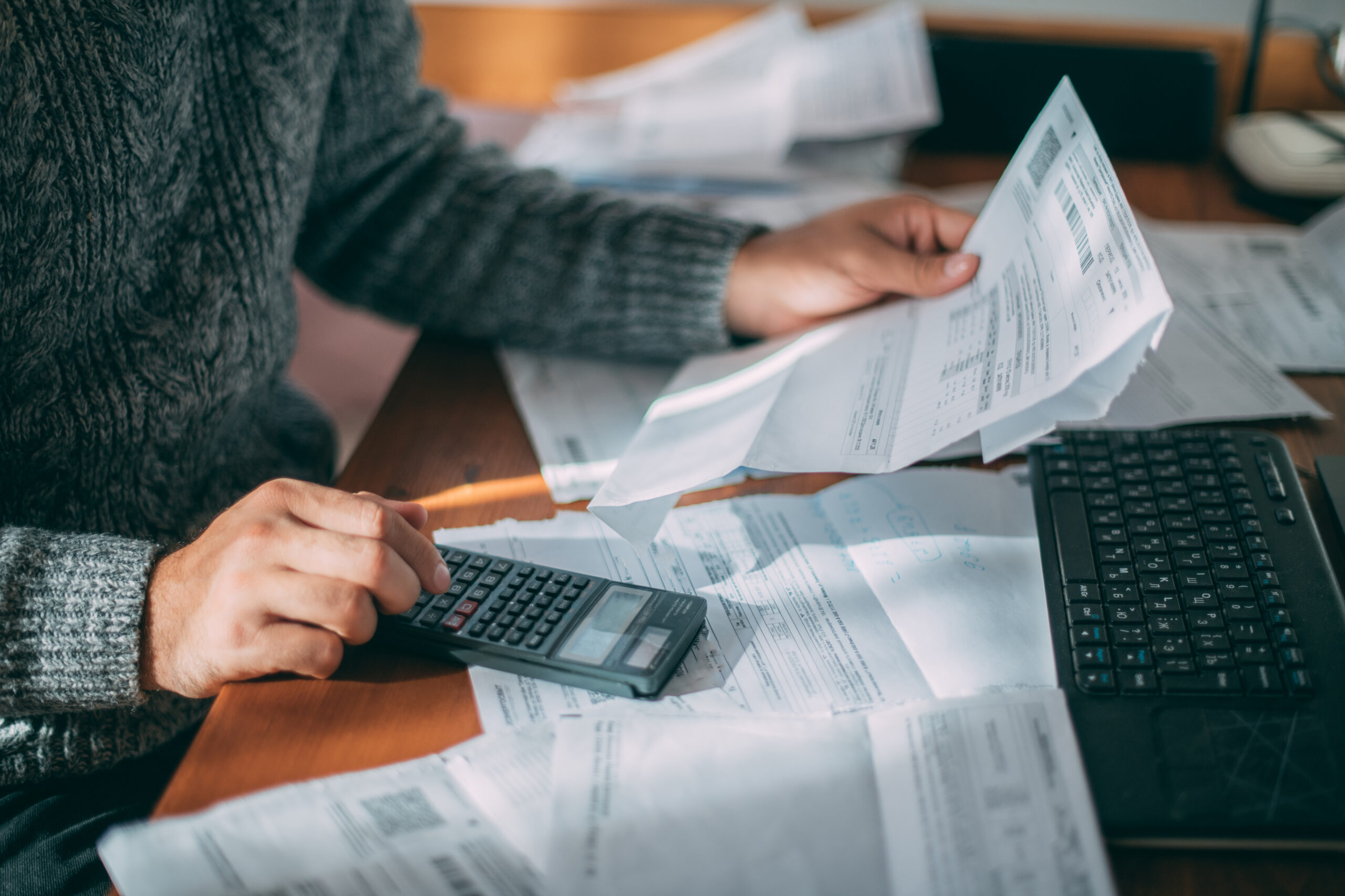 Close-up of male hands with a utility bill, a lot of checks and customer payment processing